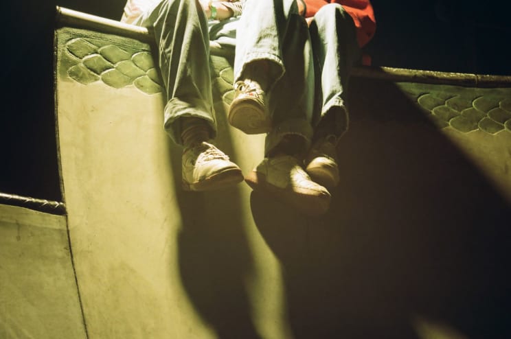 Man And Woman In Jeans And White Sneakers Sit On Wall At Night