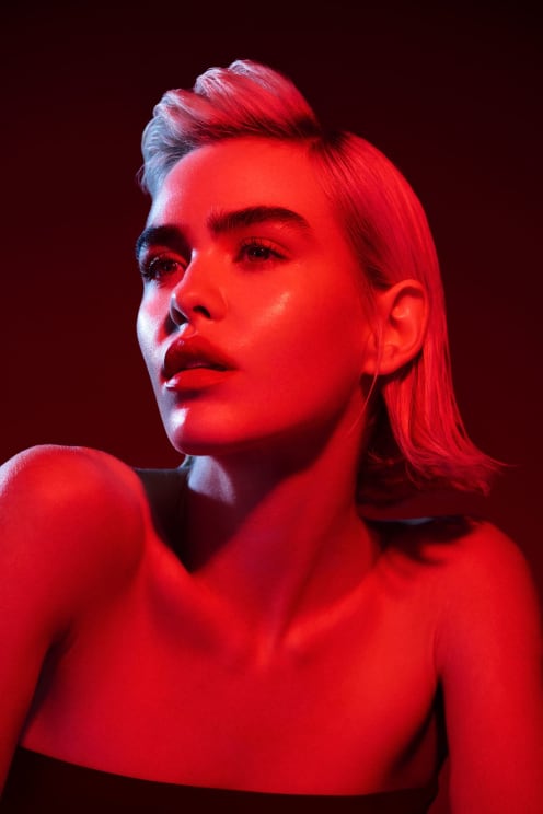 A Blonde Woman With Bare Shoulders Looks To Her Side Under Red Light