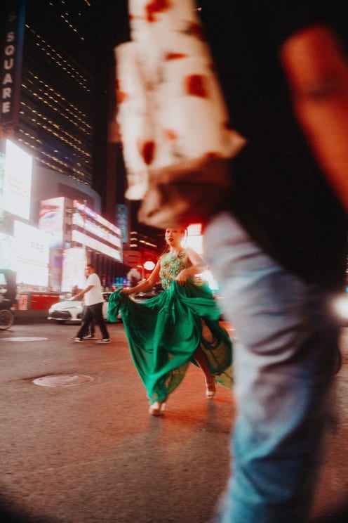 Woman In A Green Dress And High Heels Runs Down A Nighttime Street