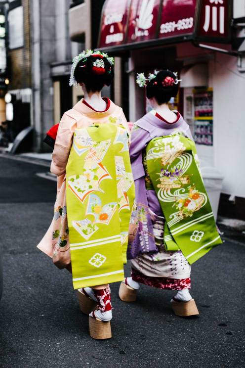 Two Asain Women Are Walking Down The Street All Dressed Up In Their Robes
