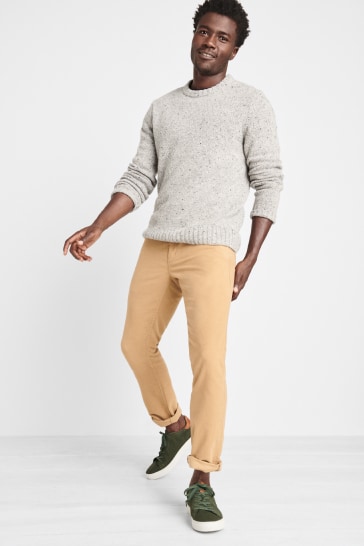 Stitch Fix men’s clothes including a grey sweater and tan pants with green sneakers.