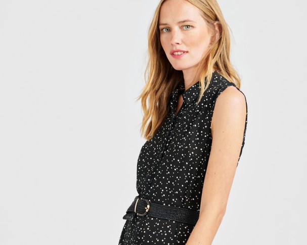 Stitch Fix model wearing a petite black sleeveless polka dot dress with leather belt.