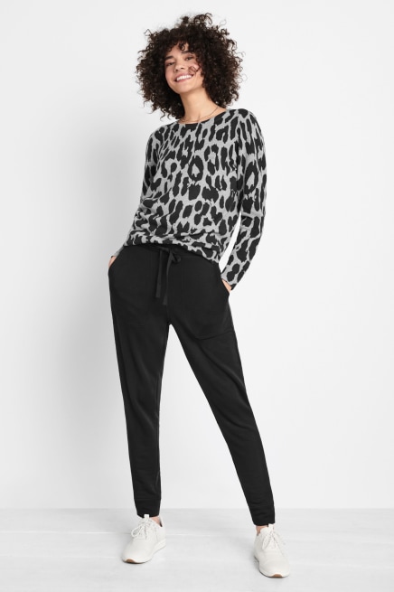 Stitch Fix model wearing a petite grey leopard print jumper, petite black jogger bottoms and white minimal trainers.