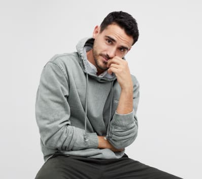 Men’s activewear clothing including a grey men’s hoodie sweatshirt and dark pants.