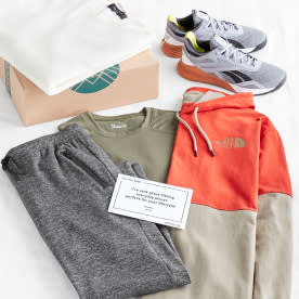 Stitch Fix men’s athleisure clothes including an orange and grey hoodie, grey pants, olive t-shirt, grey sneakers and white shirt.