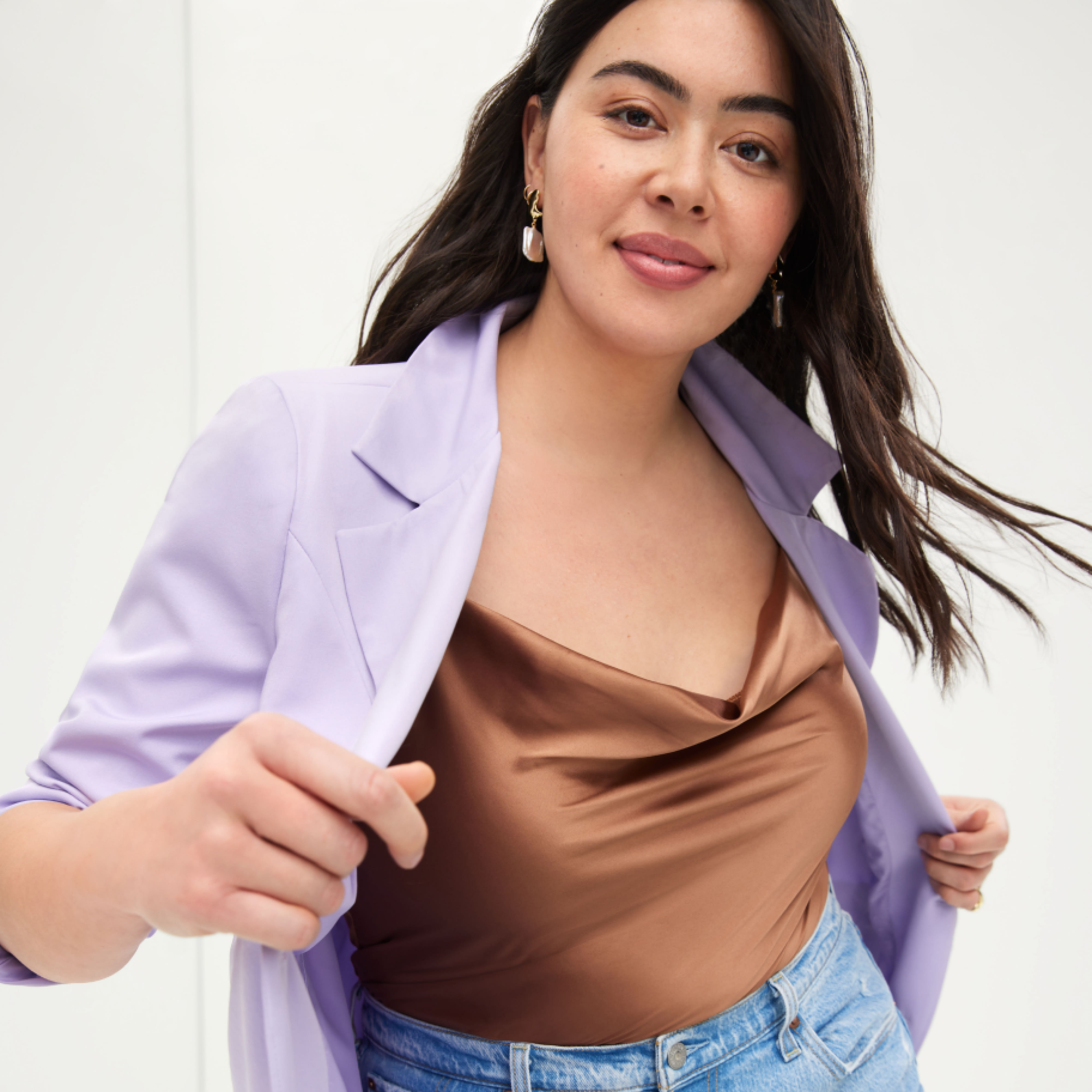 A woman poses in a petite blazer, top, and jeans.