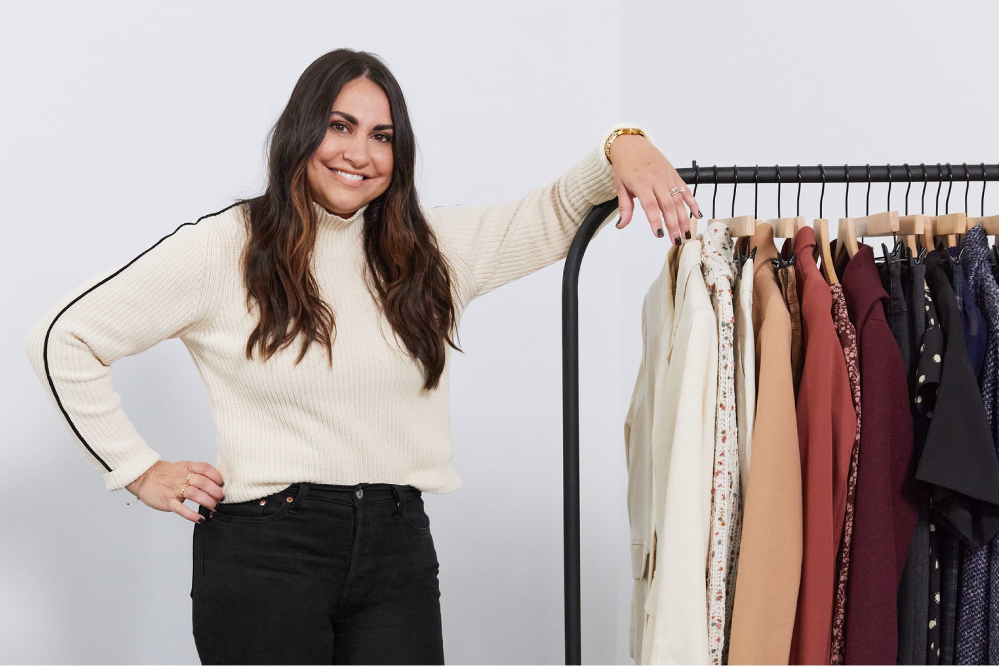A stylist stands proudly with a rack of clothes.