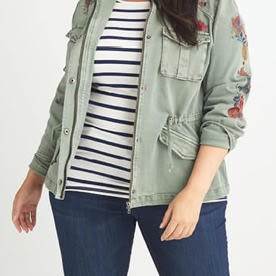 Dark wash jeans with olive green jacket over black and white striped shirt.