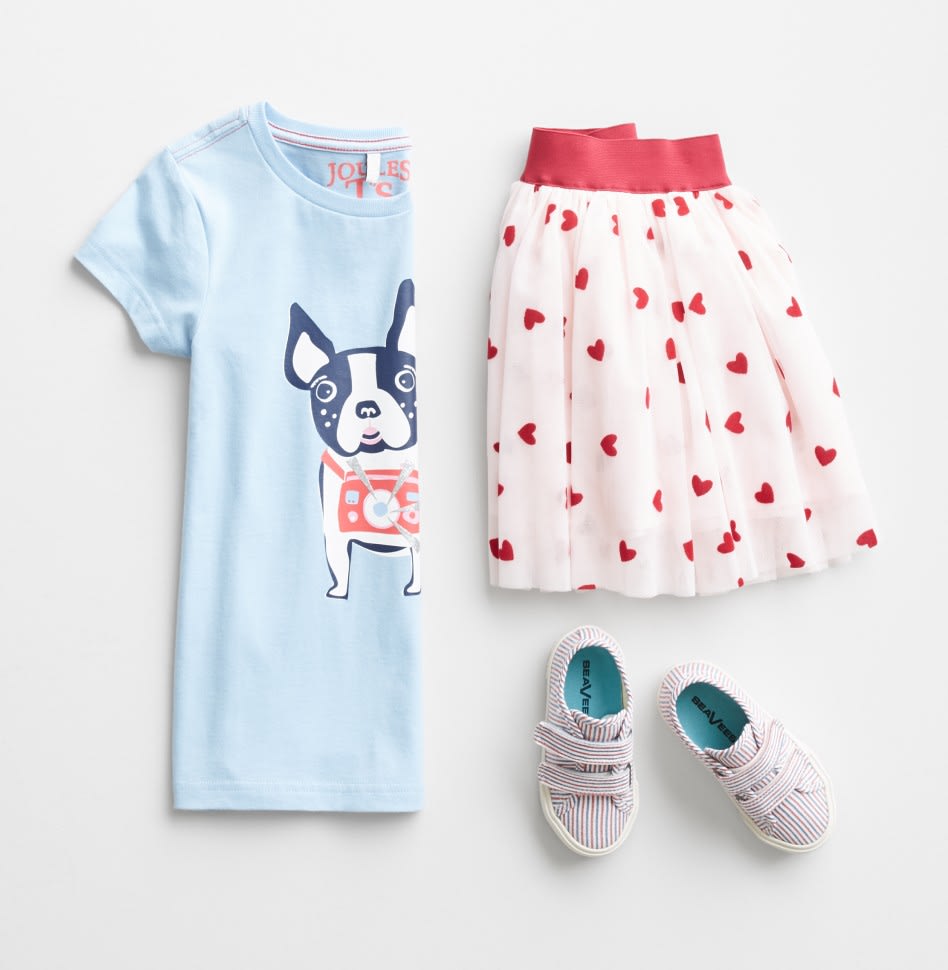 Stitch Fix Kids outfit including a light blue dog graphic tee, white and pink print skirt and white velcro sneakers.