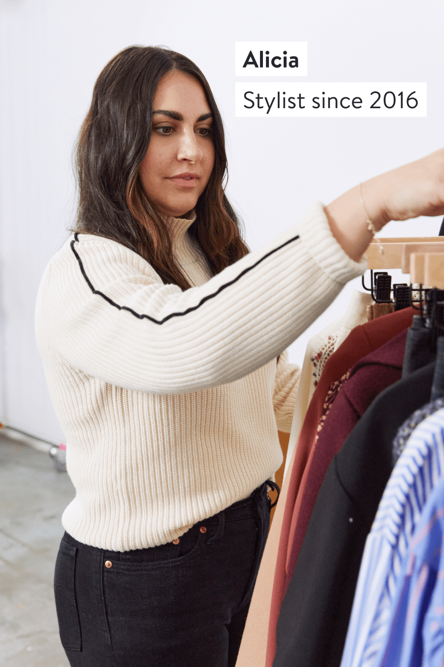 Alicia, Stylist since 2016. Stitch Fix Stylist selecting items from a clothing rack including sweaters, button-down shirts and blouses.