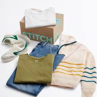 Stitch Fix women’s clothing and accessories featuring a pair of white and green sneakers, blue jeans, an olive green t-shirt, and a cream-colored sweater with colorful stripes next to a Stitch Fix box and a folded white t-shirt.