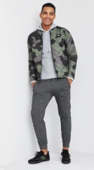 Men’s athleisure clothing including a grey mens hoodie, camo jacket, grey joggers and black sneakers.