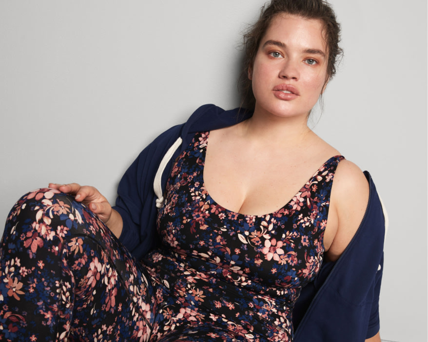 Model wearing Stitch Fix women’s clothing including a floral athletic jumpsuit and navy blue sweatshirt.