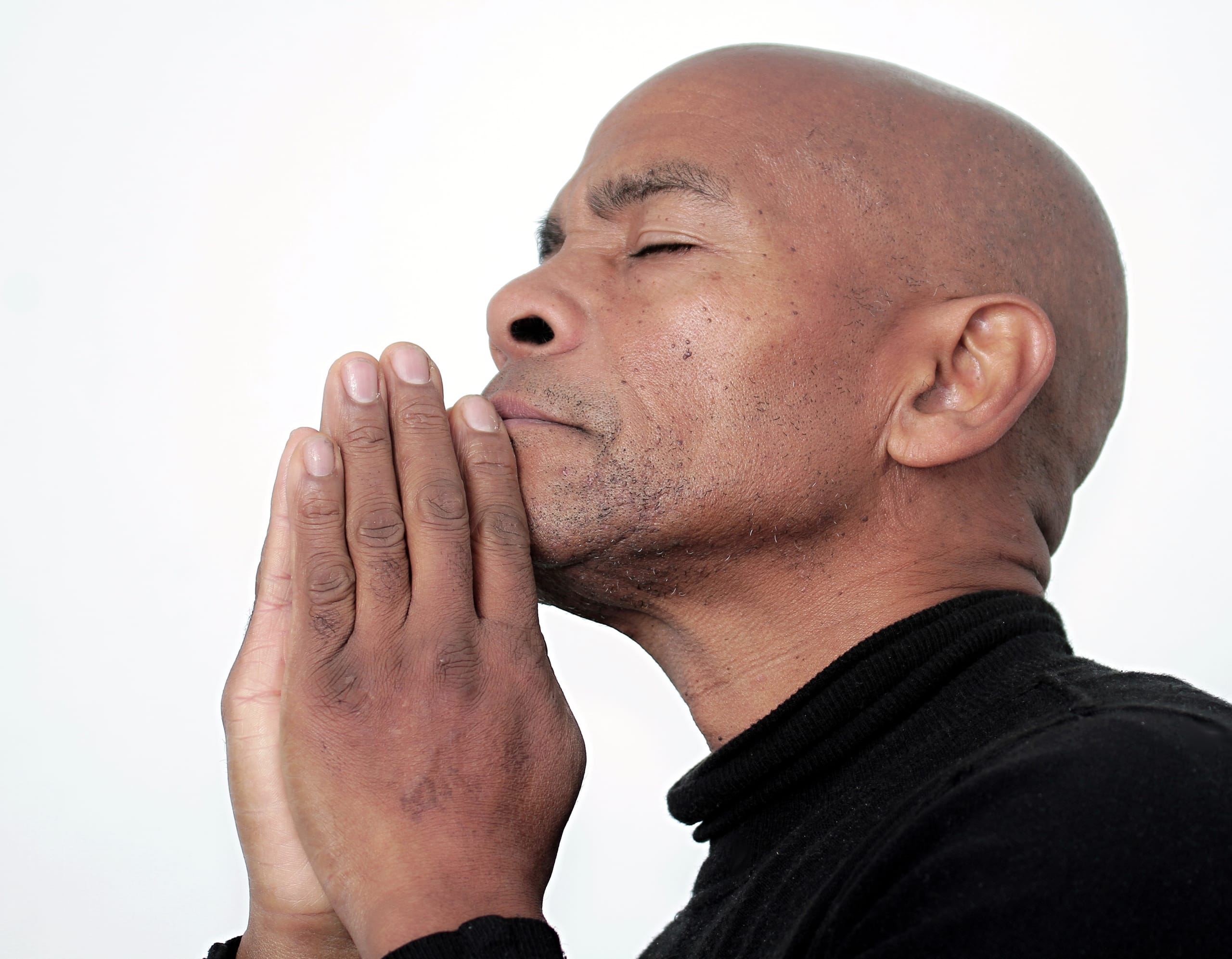 man praying to god with hands together Caribbean man praying with white background stock photo