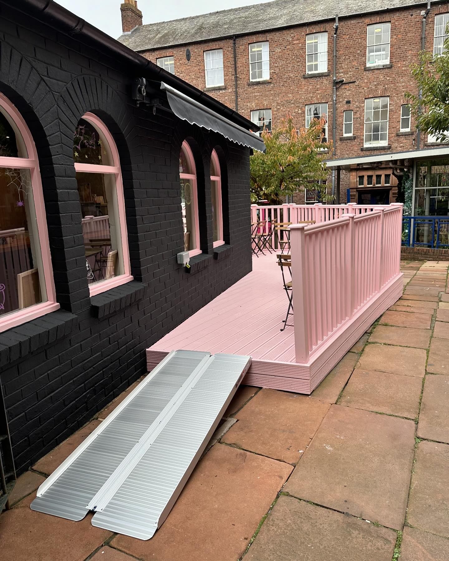 A portable ramp giving step-free access up to the pink decked terrace, with the arched windows dressed for Halloween.