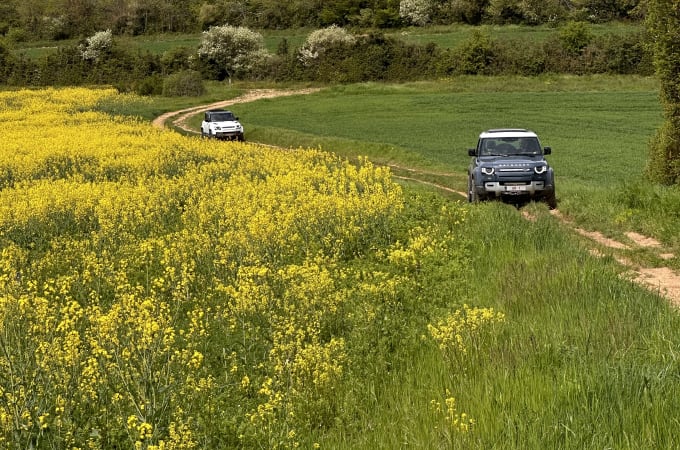 Een Defender rijdt door een ruw terrein omgeven door groen gras