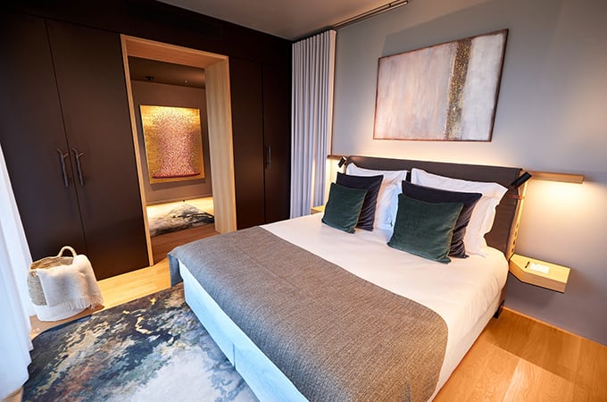Interieur van de hotelkamer met een groot bed met witte lakens en groene kussens, smaakvol ingericht