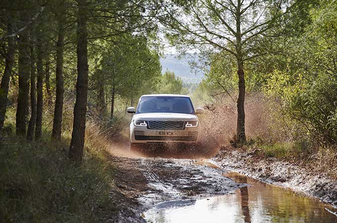 Een Range Rover rijdt op een modderige weg bedekt met water
