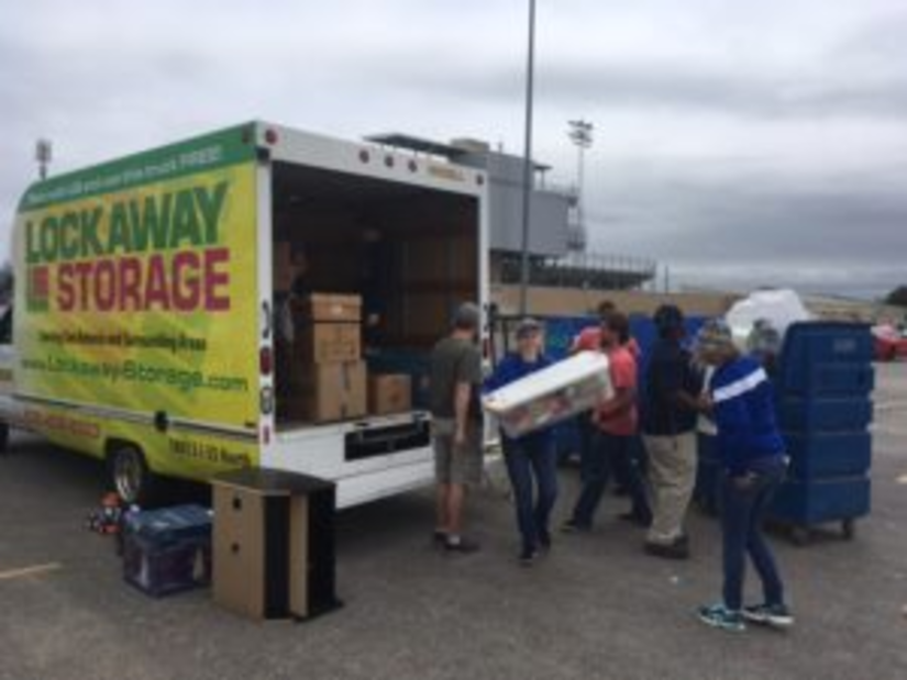 Students and volunteers help transfer donations from a Lockaway Storage box truck to a Goodwill truck.