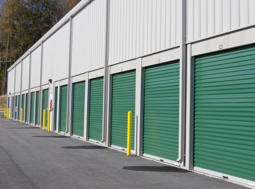 A row of drive-up storage units with green doors.