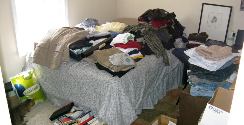 Messy Bedroom With clothes stacked on the bed