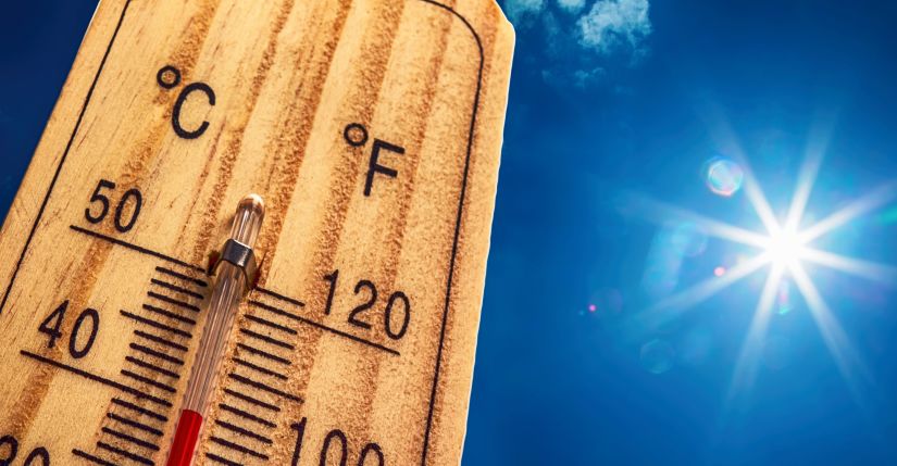 A spiking thermometer in front of a blue sky with the sun shining brightly.