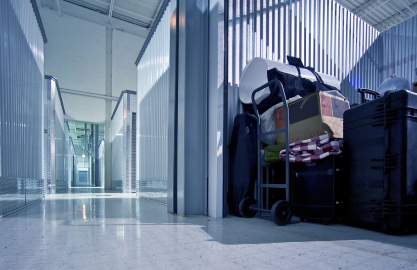 Hallway of storage units and a open storage unit that is full of stuff