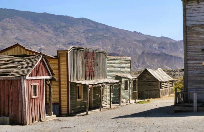 A street of worn-down wooden frontier buildings.