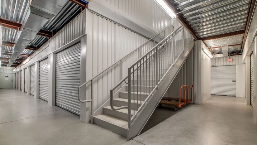 Interior hallway of Lockaway Storage in Conroe featuring clean indoor storage units, metal roll-up doors, and stair access to upper levels
