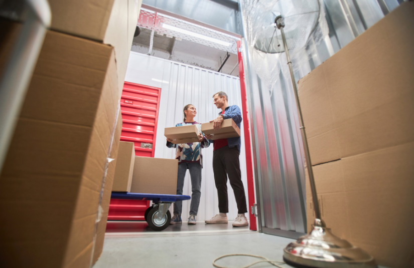 two people holding boxes outside an open storage unit