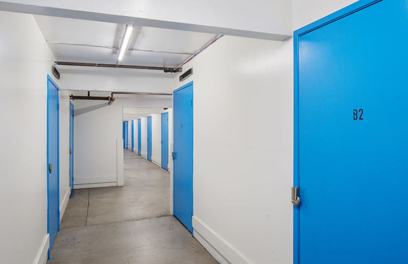 A hallway lined with blue doors to small storage units.
