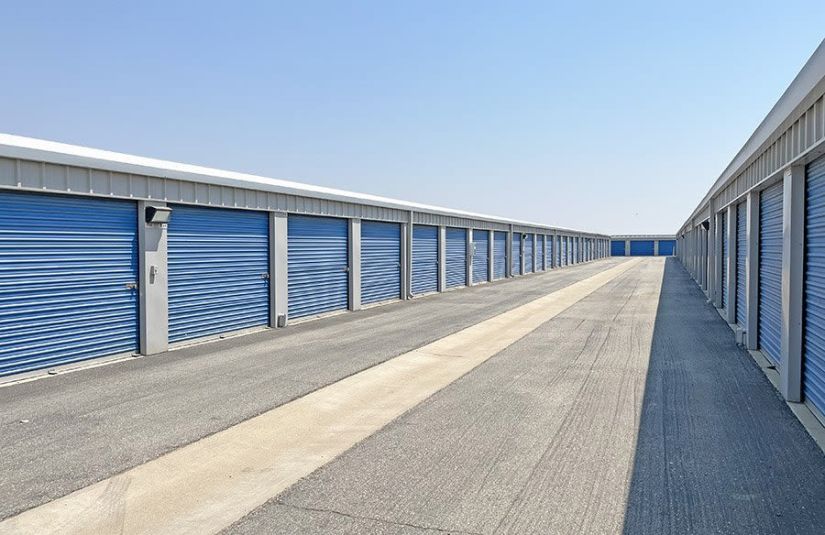 Rows of exterior drive-up storage units with blue doors.