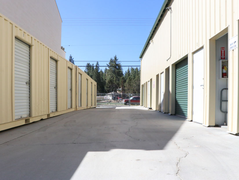 Drive-up self storage units at Highland Storage with roll-up doors and wide access driveway under clear blue sky.