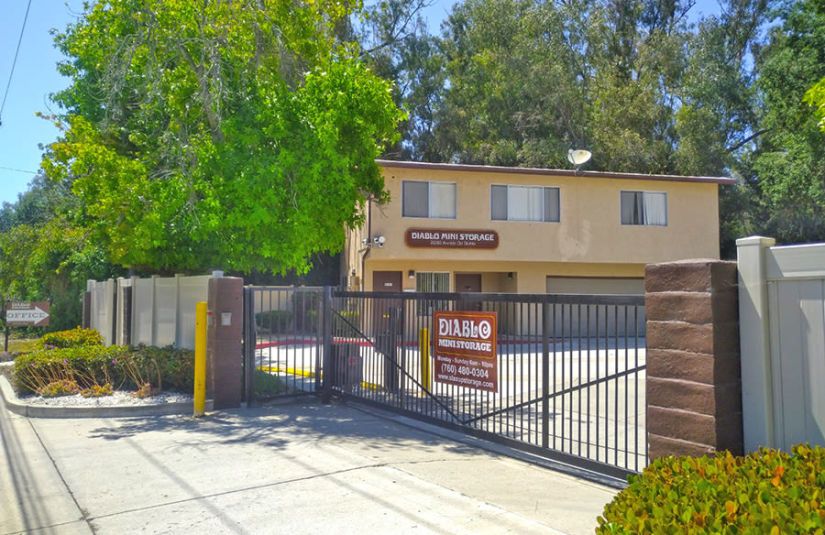 The gated front entrance of Diablo Mini Storage, with a sign on the gate.