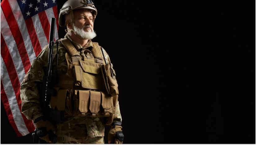 older soldier stnading with back to usa flag with a black background