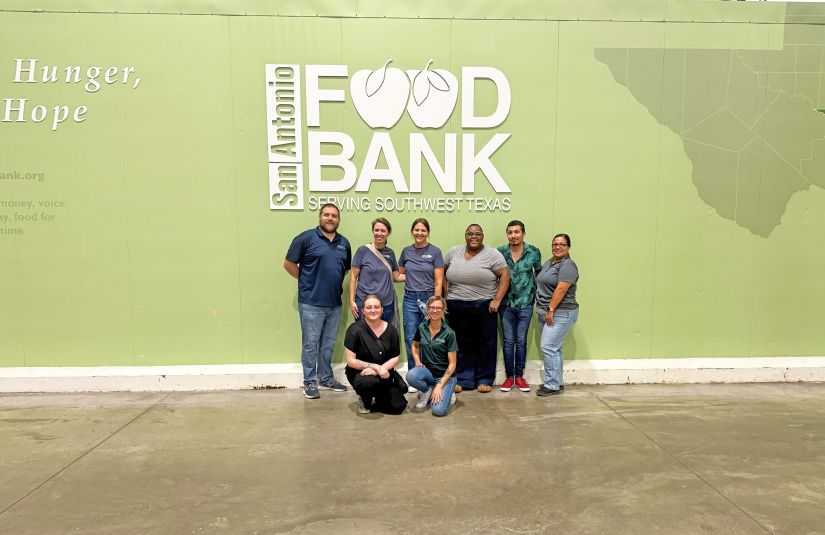San Antonio Lockaway team together in front of the San Antonio Food Bank wall