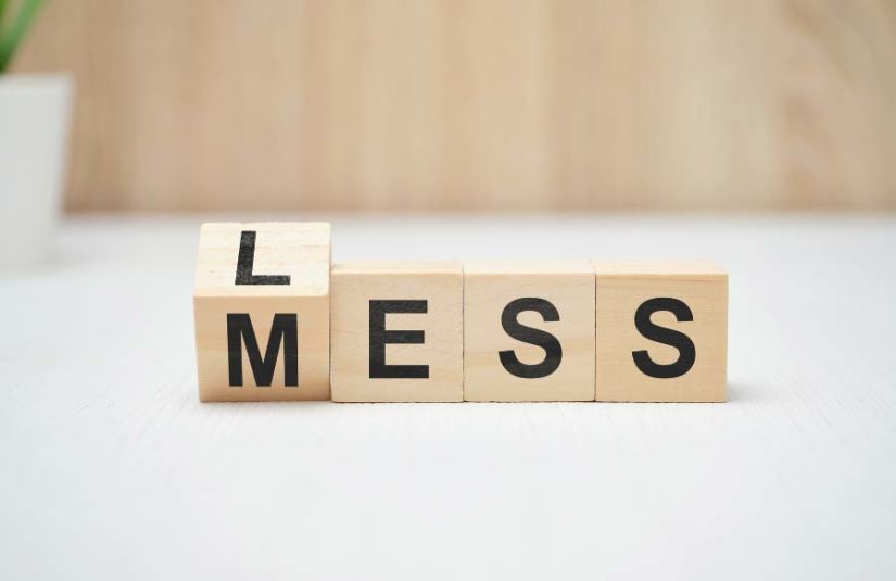 Wood cubes that spell the word Mess but with the letter L on the other side of the Letter M to then spell Less