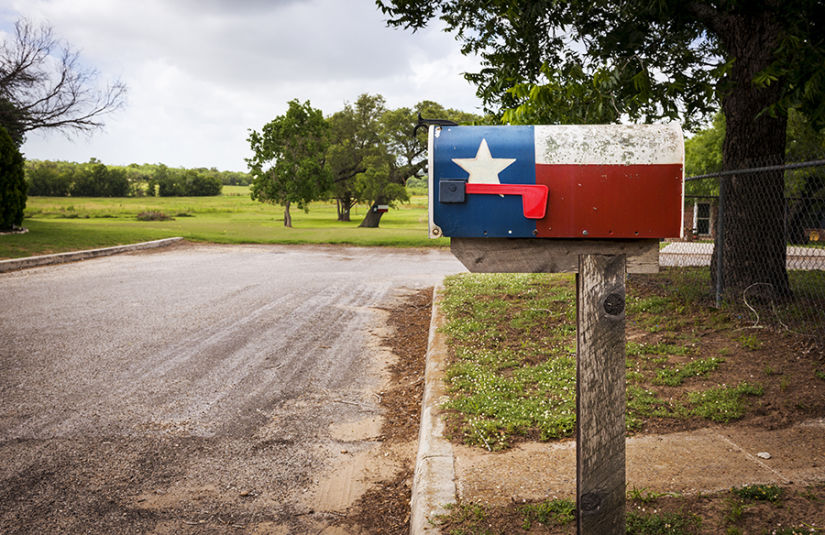 A mailbox on a rural road with the Texas flag painted on it.