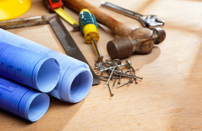 Blueprints and construction tools scattered on a table.