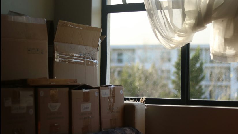 Brown cardboard boxes stacked in sunny dorm room ready for student storage in El Cajon