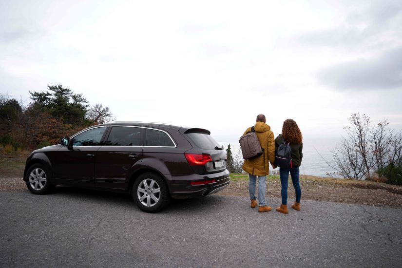 man and woman walking near black car