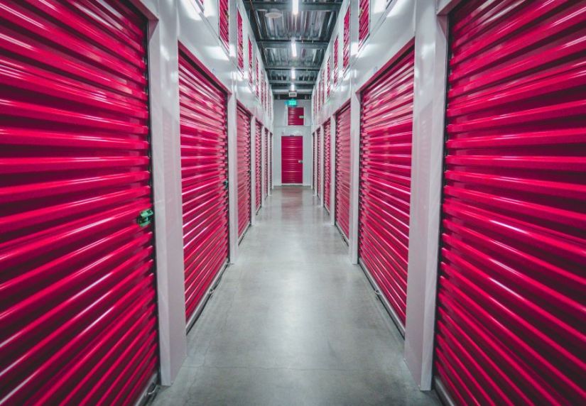 A hallway of storage units with red doors.