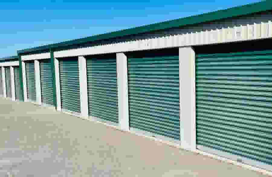 A row of drive-up storage units with green doors.