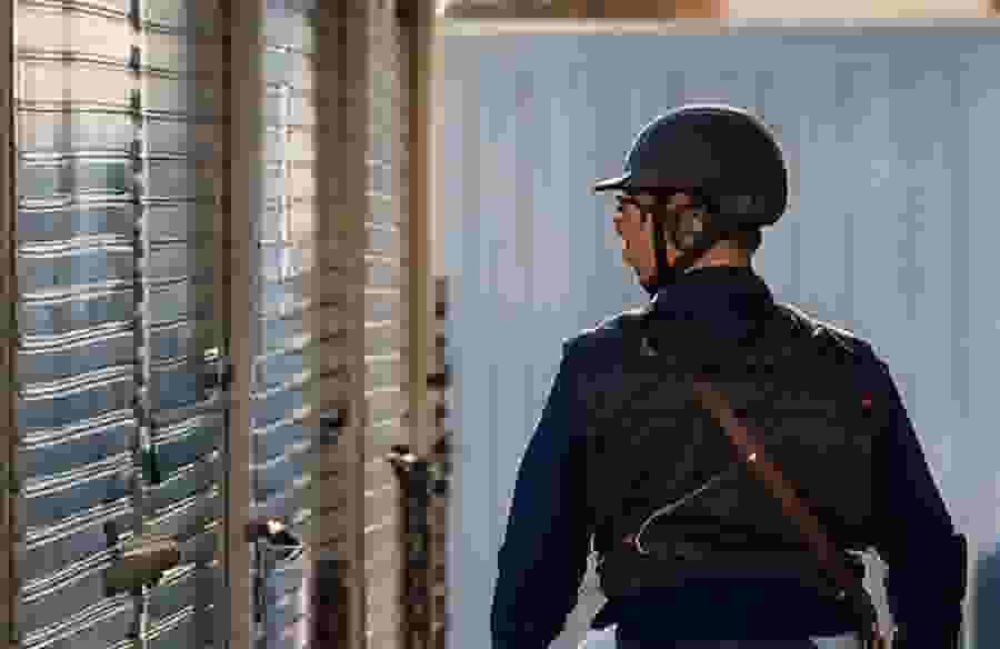 This image shows a person in equestrian gear standing in a self storage facility looking at the units.
