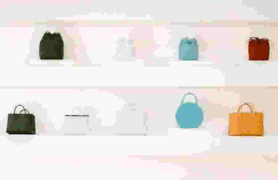 A line of handbags in different shapes and colors.