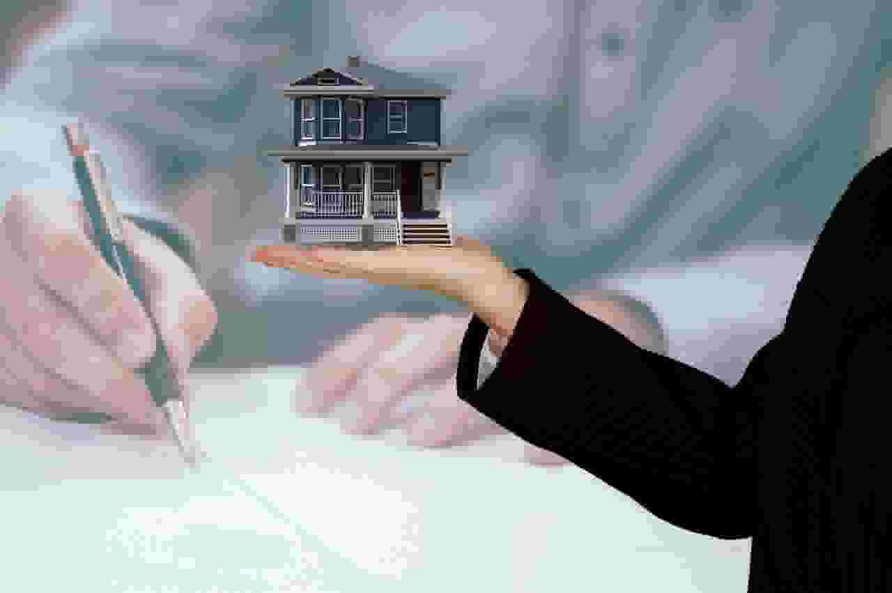 person signing contract and another person holding a small model house