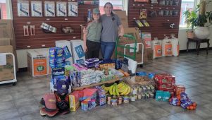 Self-storage assistant manager and her son proudly stand with a large collection of essential items donated to support homeless veterans.