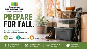 Brownstone Self Storage in Defiance, OH, featuring drive-up storage units with seasonal household items, outdoor furniture, a bicycle, and fall leaves.