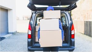 man holding storage boxes by open car trunk
