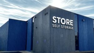 Exterior view of STORE self storage facility featuring modern blue and gray building with bold signage